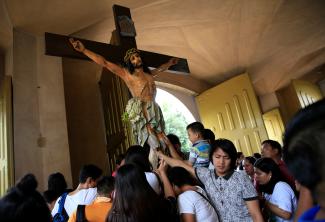 Catholics touch a crucifix after attending a mass at the National Shrine of Our Mother of Perpetual Help, in Baclaran, Philippines, on September 18, 2016.