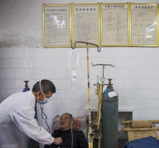 Fu Jianghua (L), the head of Yangjia Hospital at the time, checks a patient in the hospital in Wuyi County, Zhejiang Province, China October 19, 2015.