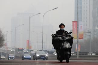 A man wearing face mask rides a scooter on the street during a day with polluted air, following the outbreak of the coronavirus disease (COVID-19), in Beijing, China February 13, 2021.
