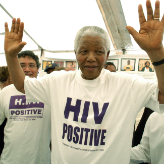 Former president of South Africa Nelson Mandela—wearing a white t-shirt with HIV POSITIVE in purple printed on the front—visits the township of Khayelitsha in Western Cape, South Africa. Photo by Media24/Gallo Images/Getty Images