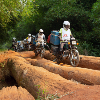 A motorcycle convoy carrying measles vaccines for the NGO Doctors Without Borders crosses a log bridge in Mongala Province, in the Democratic Republic of Congo, on February 27, 2020. 