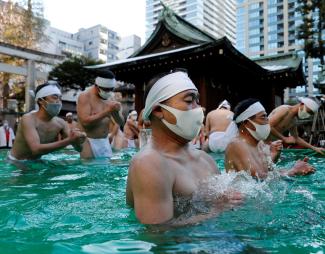 Participants wearing protective face masks amid the coronavirus disease (COVID-19) outbreak, pray as they take an ice-cold bath during a ceremony to purify their souls and to wish for overcoming the pandemic at the Teppozu Inari shrine in Tokyo, Japan, January 9, 2022.