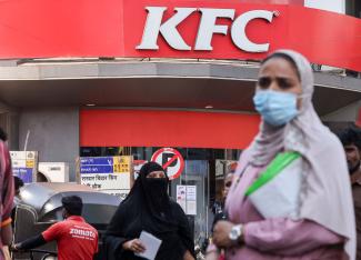 People walk past a Kentucky Fried Chicken (KFC) fast food restaurant, in Mumbai, India, on February 9, 2022.