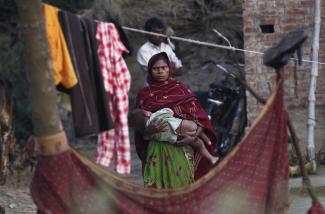 A woman holds her child as she stands outside her house at Dalit village of Bhaddi Kheda in Uttar Pradesh, India, on January 15, 2012.