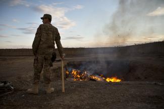 A U.S. Army soldier watches bottled water that had gone bad burn in a burn pit at Forward Operating Base Azzizulah in Maiwand District, Kandahar Province, Afghanistan, on February 4, 2013. 