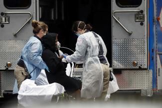 Emergency medical technicians (EMT) wearing protective gear wheel a sick patient to a waiting ambulance during the COVID-19 outbreak, in New York City, on March 28, 2020.