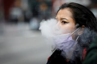 A woman exhales after vaping in Times Square, during the COVID-19 outbreak, in New York City, on March 31, 2020.