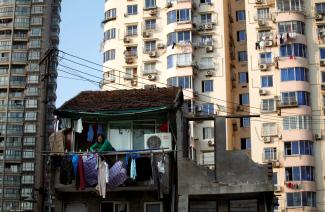 A woman stands at the balcony of her house, which will be demolished to build new apartments in downtown Shanghai, China, on December 1, 2010. 