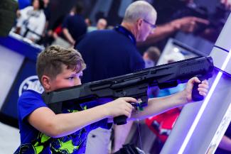 A boy tries out a 12 gauge Smith and Wesson shotgun as people attend the National Rifle Association (NRA) annual convention in Houston, Texas, on May 28, 2022.
