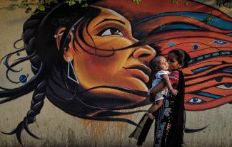 A mother kisses her child as she walks past graffiti in Mumbai March 27, 2014.