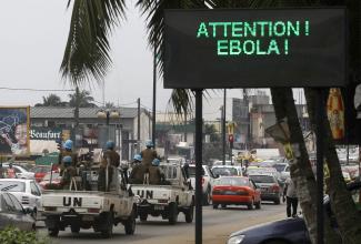 A U.N. convoy of soldiers passes a screen displaying a message on Ebola on a street in Abidjan August 14, 2014. 