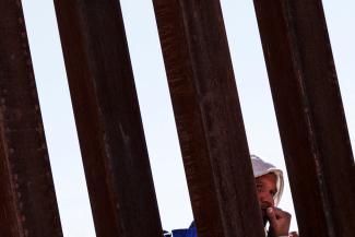 A migrant seeking asylum in the United States waits in line along the border fence at the Rio Bravo River, as seen from El Paso, Texas, on December 22, 2022.its in line along the border fence at the Rio Bravo river, the border between Mexico and the U.S., as seen from El Paso, Texas, on December 22, 2022.