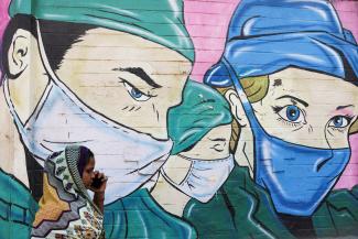 A woman walks past a coronavirus (COVID-19) themed mural on a street in Mumbai, India, March 28, 2023.