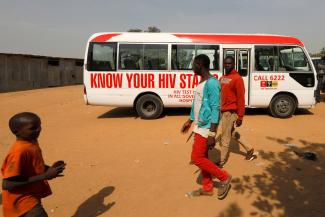People walk past a bus during an HIV/AIDS awareness campaign on the occasion of World AIDS Day at the Kuchingoro IDPs camp in Abuja, Nigeria, December 1, 2018. 