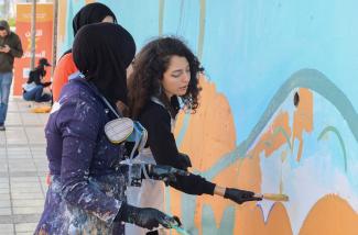 A volunteer paints a mural on a wall in Irbid, Jordan, February 25, 2023.