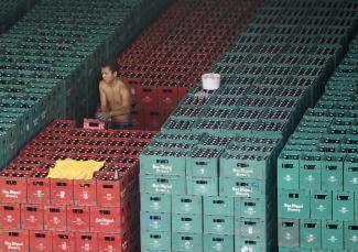 A worker arranges crates of beer before loading them onto a truck inside a San Miguel beer warehouse in Manila, Philippines, November 14, 2012.