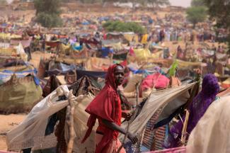 A Sudanese girl moves past makeshift shelters near the border between Sudan and Chad, while taking refuge in Borota, Chad, May 13, 2023.