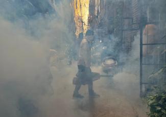 A health worker fumigates an alley in a residential neighborhood.