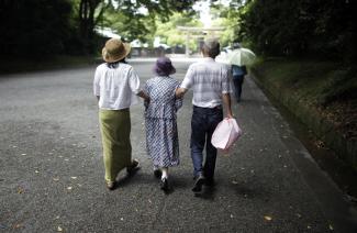 Three people walk down a street with their arms linked.