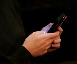 A 23-year-old Jewish American, sits with the phone he uses to access social media and see posts about the Israel-Palestinian conflict at his home.