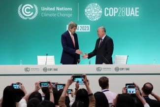 U.S. Climate Envoy John Kerry and Chinese Climate Envoy Xie Zhenhua reach to shake hands at a press conference, after a draft of a negotiation deal was released, at the United Nations Climate Change Conference COP28 in Dubai, United Arab Emirates, December 13, 2023. 