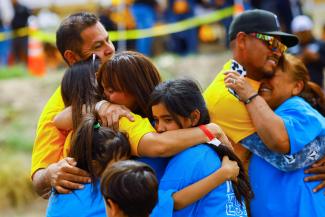 Families hug each other as they participate in a reunification meeting for relatives separated by deportation and immigration.