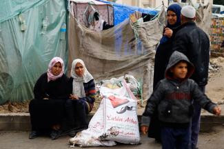 Palestinian women sit near bags of flour distributed by the United Nations Relief and Works Agency (UNRWA).