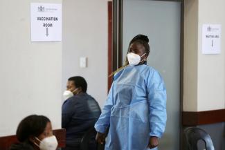 A health worker looks on as she waits to give a dose of the COVID-19 vaccine.