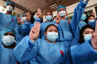 Medical workers wearing red ribbons pose during a protest against the coup that ousted elected leader Aung San Suu Kyi.