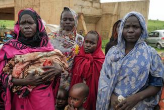 Sudanese women, who fled the conflict in Murnei in Sudan's Darfur region, look on while crossing the border between Sudan and Chad.