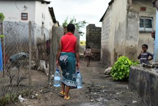 A woman carries bottles of water in a neighborhood affected by the cholera outbreak.