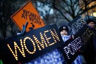 A woman holds signs as she attends a rally to commemorate International Women's Day at Union Square Park.