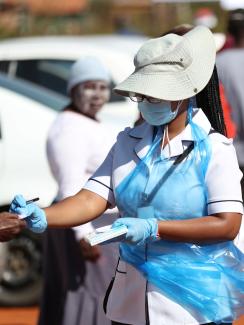A member of medical staff attends to residents as they queue during screening and testing campaign aimed to combat the spread of COVID-19, in Lenasia, South Africa, on April 21, 2020.
