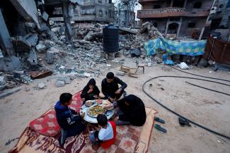 A Palestinian family eats their iftar meal as they break their fast near the rubble of their destroyed home.
