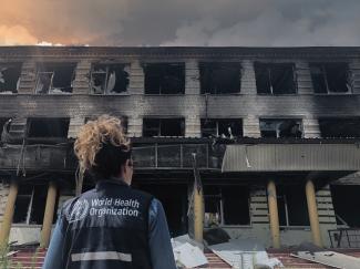 A member of a World Health Organization team looks at a destroyed school.