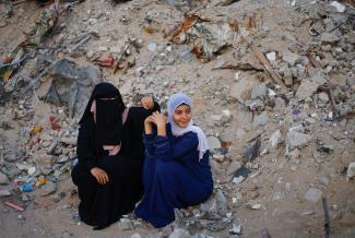 Palestinian women look on as others hold Eid al-Adha prayers by the ruins of the Al-Rahma mosque destroyed by Israeli air strikes.