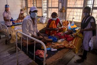 A patient suffering from diabetes lies on a hospital bed as his family look after him.
