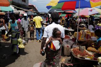 A woman carries her daughter as she walks through the Gobachop market.