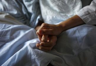 A woman holds the hand of her mother who is dying from cancer during her final hours, at a palliative care hospital, in Winnipeg, Canada, onJuly 24, 2010.