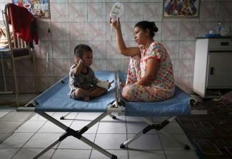 A mother sits with her son who is recovering from a respiratory illness in a hospital in Palangkaraya, Central Kalimantan, Indonesia October 28, 2015