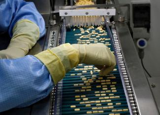 An employee inspects tablets as they move along the production line at a pharmaceutical plant of Lupin.