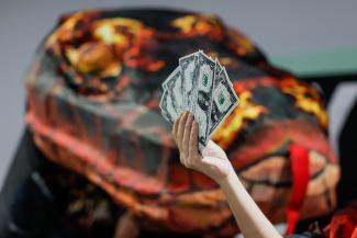 An activist holds up fake currency bills as she participates in a protest action during the United Nations climate change conference COP29 in Baku, Azerbaijan November 20, 2024.