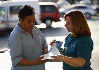 A patient care coordinator at AltaMed, speaks to a man during a community outreach on Obamacare.