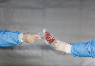 Health-care workers hand off a biohazard bag at a COVID-19 testing site outside the International Community Health Services, in Seattle, Washington, on March 26, 2020.