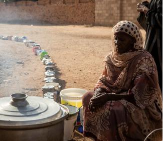 A Sudanese woman from a community kitchen, run by local volunteers as empty pots are seen lined up to receive food, in Omdurman, Sudan, on September 19, 2024.