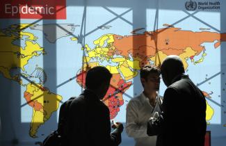 Delegates walk past an information board during the 62nd World Health Assembly at the United Nations European headquarters, in Geneva, Switzerland, on May 18, 2009.