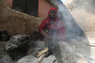 A Nigerian woman who fled attacks by bandits in her village, makes a fire with wood at a makeshift kitchen, in a shelter for displaced people, in Gusau, Zamfara, Nigeria, on February 8, 2023.