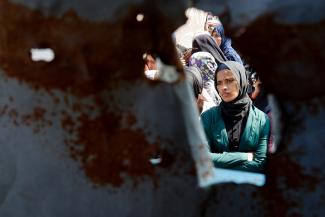 A Palestinian woman looks on as she and others gather to receive bread from a bakery, in Khan Younis, Gaza Strip, on March 9, 2025.
