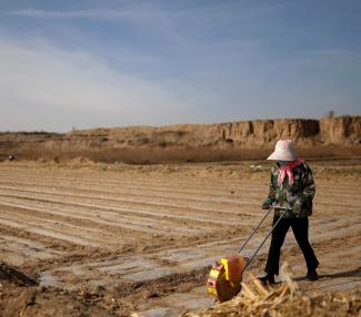 A worker uses a planter to plant corn seed in a village near the edge of the Gobi Desert, on the outskirts of Wuwei, Gansu province, China, on April 14, 2021.
