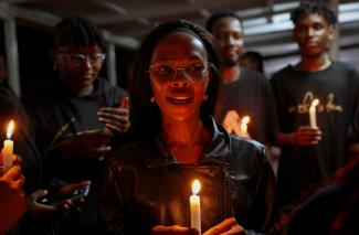 People hold candles at a vigil to raise awareness about gender-based violence and honor the lives of women lost to femicide in higher learning institutions, in Juja, Kenya, on April 11, 2025.